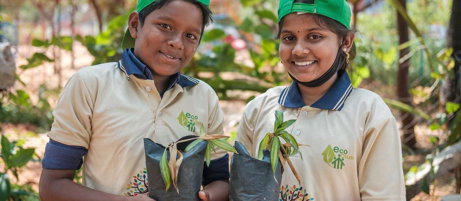Junge und Mädchen mit Baumsetzlingen in Indien