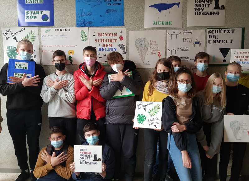 Schülergruppe steht vor Wand mit Klimaplakaten